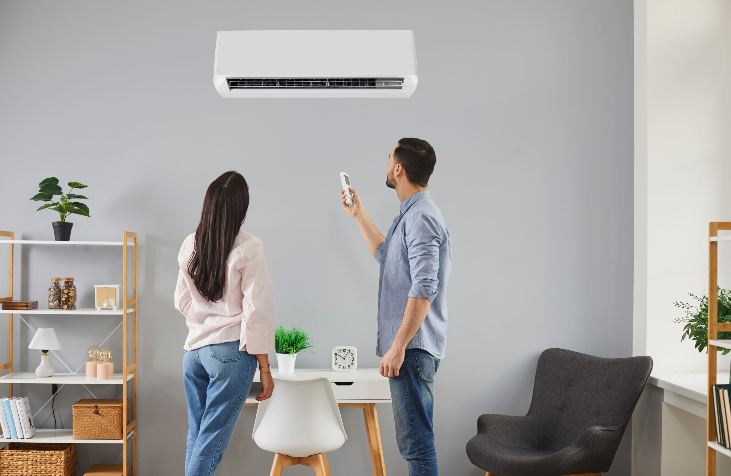 Young family couple regulating temperature at home with modern air conditioning system