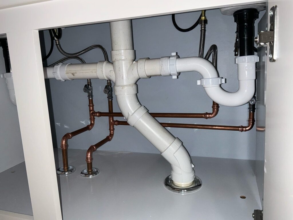 New PVC drain lines and Uponor PEX water supply lines roughed in for double-sink configuration in Williamsville, NY bathroom.