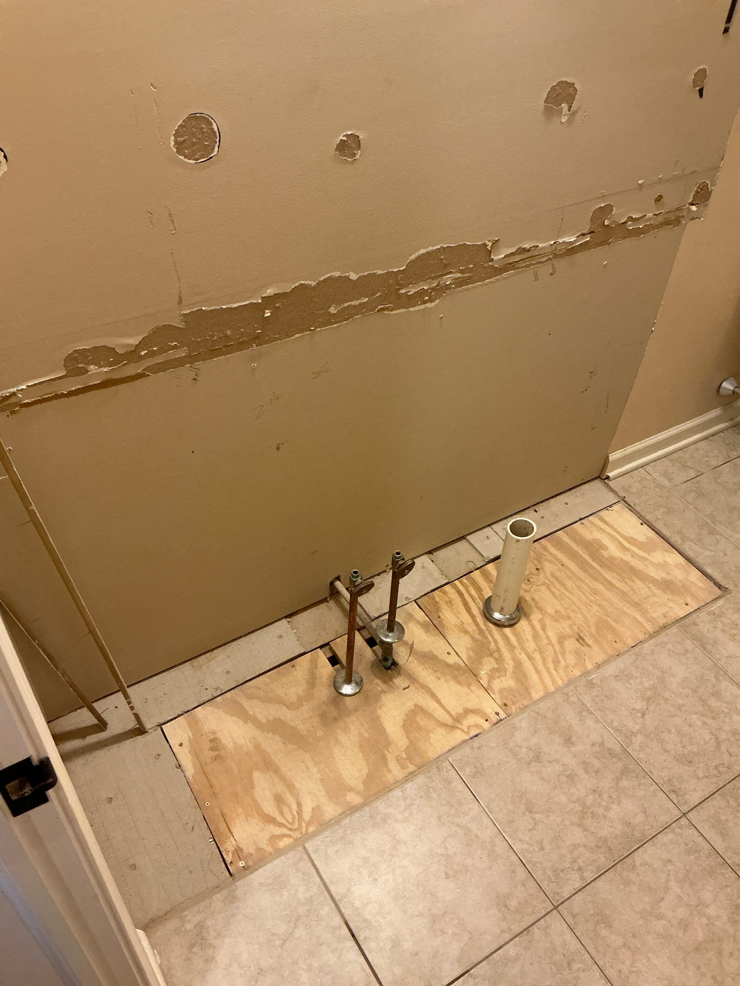 Subfloor and wall opened to access existing drain and water piping for double-sink rough-in by Cellino in Williamsville, NY.